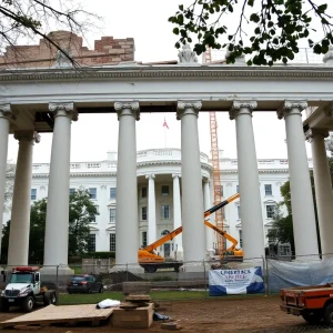 Demolition of the East Wing of the White House, highlighting the historic colonnade and construction equipment.